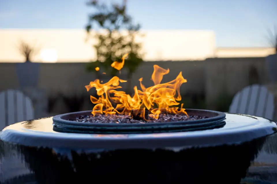 A fire pit burning on a patio at dusk
