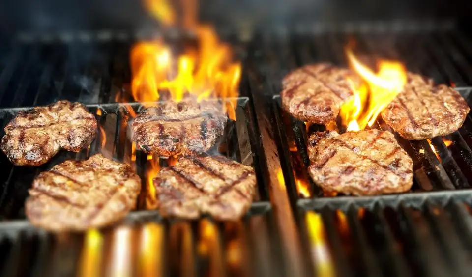 Burger patties searing over open flames