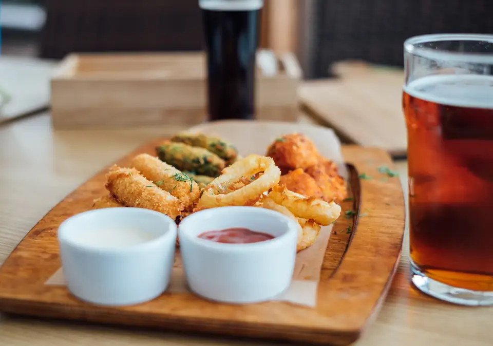 Beer-battered onion rings with dipping sauces and a pint of amber