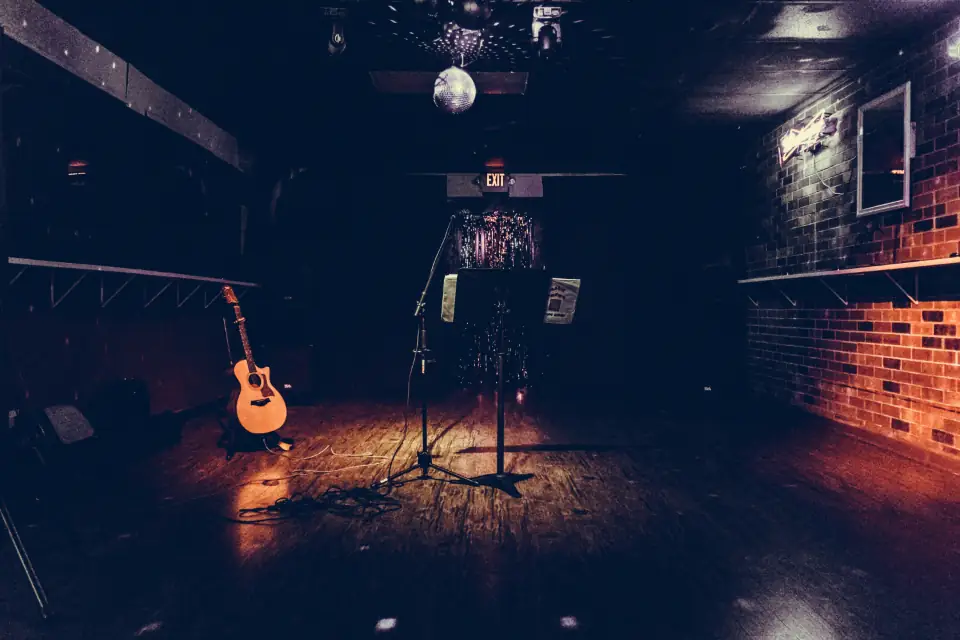 A small stage with a guitar and microphone under warm lights